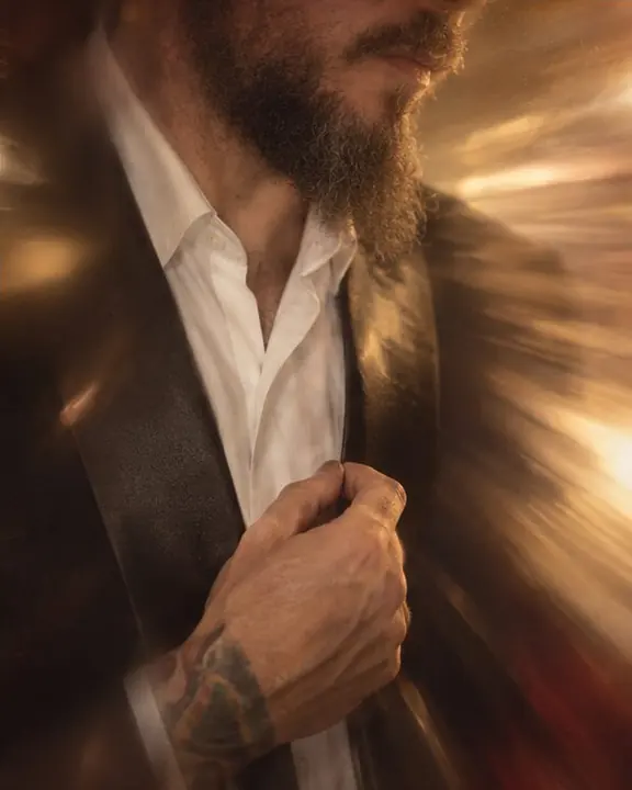 A satin tuxedo lapel highlight melting into a long radial streak of warm gold light on deep shadow