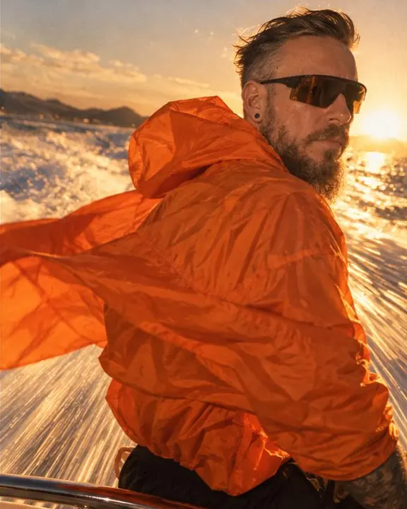 Detail of tangerine nylon billowing in the wind with golden streaks of water blurring past it