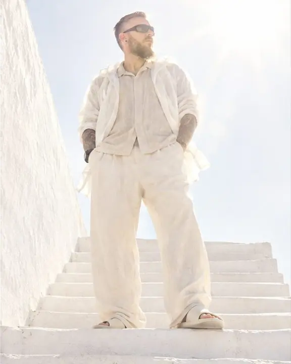 Low view of a man on white stairs against a white sky, the edges of his silhouette eaten by sunlight