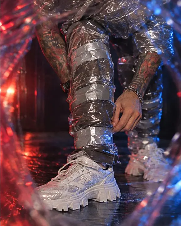 Detail of jeans wrapped in clear stretch film and silver tape, crinkled white highlights across the plastic