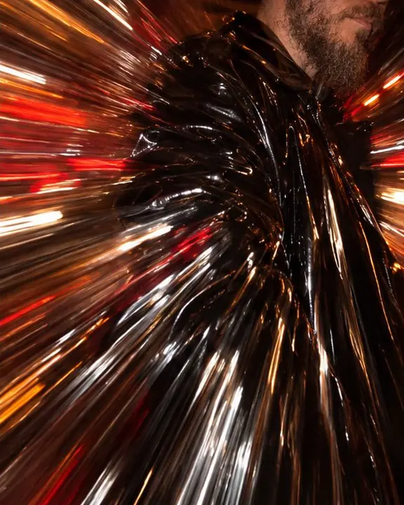 Glossy black vinyl coat surface stretched into long radial streaks of red and amber highlights
